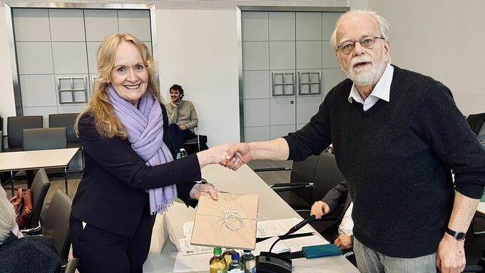 Regionalratsvorsitzende Mechthild Schulze Hessing verabschiedet Dr. Michael Harengerd, gibt ihm die Hand und ein Geschenk